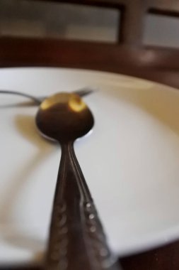 Masanın üzerinde beyaz çatal ve kaşıktan oluşan bir sofra takımı var.