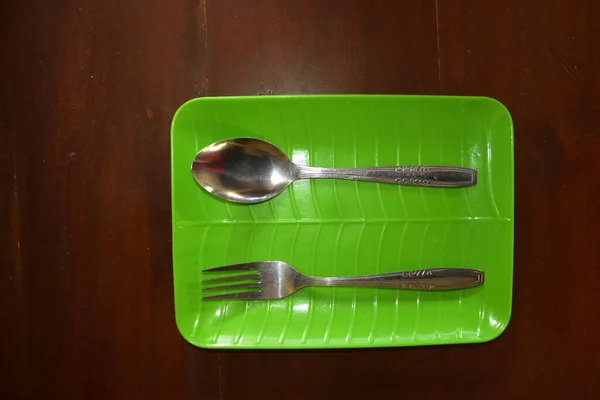 Masanın Üzerinde Yeşil Çatal Kaşıktan Oluşan Bir Sofra Takımı Var — Stok fotoğraf