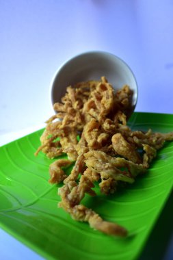 İstiridye mantarı cipsi, çıtır çıtır, yeşil bir tabakta beyaz bir kaseden dökülüyor.