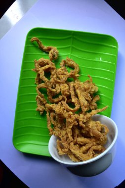 İstiridye mantarı cipsi, çıtır çıtır, yeşil bir tabakta beyaz bir kaseden dökülüyor.