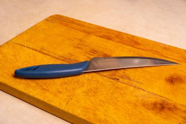 Bir ahşap mutfak ördeği. Üzerine mavi saç teli saplanmış bir bıçak.