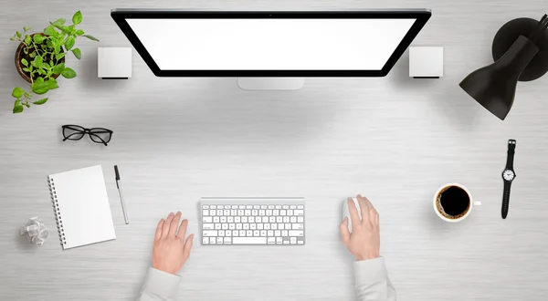 Modern desk with isolated computer display top view. Designer works with a mouse and keyboard. Coffee, lamp, paper, glasses, plant, watch on table.