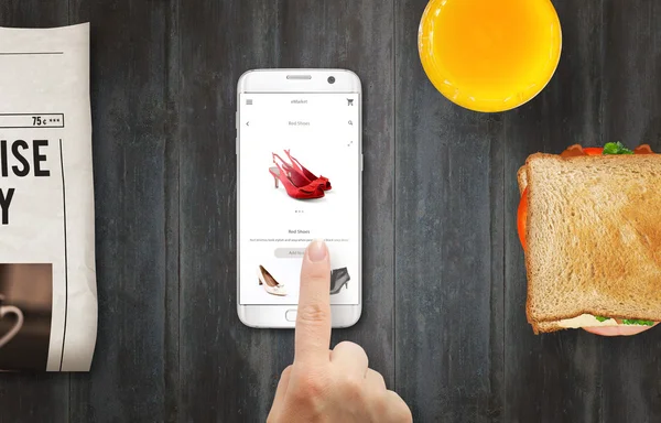 Akıllı telefon ile online alışveriş. Elle online mağazakadın ayakkabı satın alma. Kahve, sandviç, masada gazete ile rahatlayın.