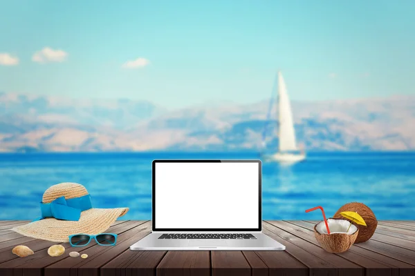 Isolierte Anzeige von Laptop auf Holztisch für Attrappen. Kokosnuss, Hut, Muscheln, Steine, Sonnenbrille auf dem Tisch. Meer, Yacht und blauer Himmel im Hintergrund. — Stockfoto