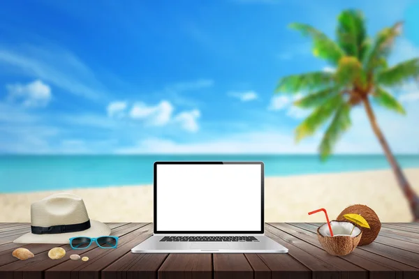 Geïsoleerde weergave van laptop op houten tafel voor mockup. Kokos, hoed, schelpen, stenen, zonnebril op tafel. Strand, zee, palm en blauwe hemel in achtergrond. — Stockfoto