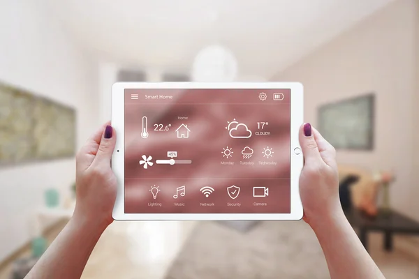 在女人手中的远程智能家居控制应用程序。客厅在背景中. — 图库照片