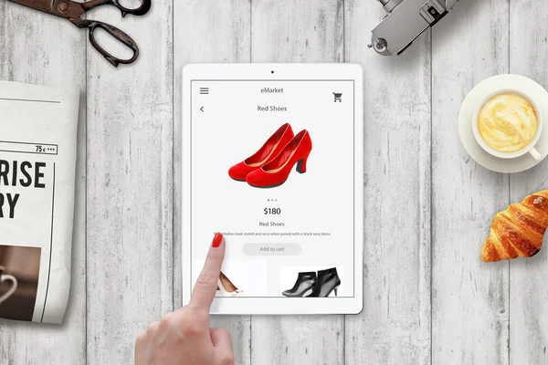 Donna shopping online scarpe rosse con tablet. Dispositivo sul tavolo con giornale, forbici, caffè, macchina fotografica, croissant . — Foto Stock