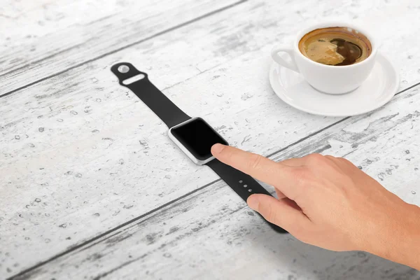 Man touch smartwatch with blank screen for mockup. Isometric view. Cup of coffee beside on table.