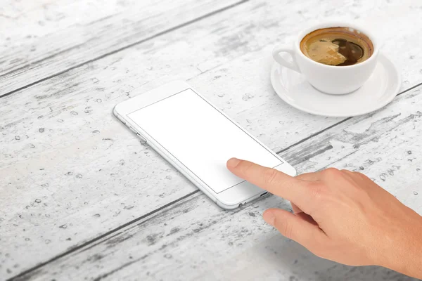 Man touch smart phone with blank screen for mockup. Isometric view. Cup of coffee beside on table.