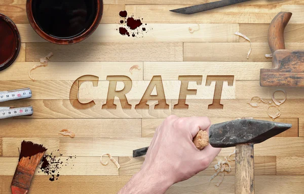Craft word carved in wood with hammer and chisel. Beside is brush, paint, wood plane, ruler, shavings.