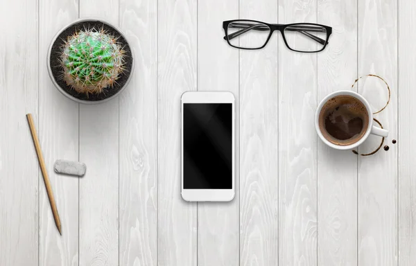 Smart telefon mockup på vit trä skrivbord. Kaffe, växt, glasögon bredvid. — Stockfoto
