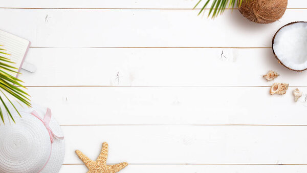 Summer travel background composition with woman hat, notebook, starfish, coconut and shells on white wooden table. Top view, flat lay