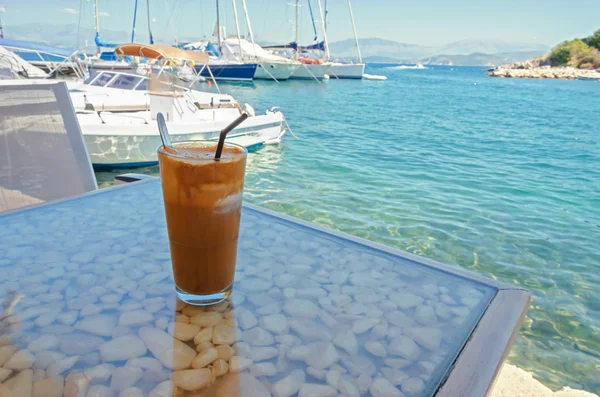 Café glacé sur une table avec vue sur la mer et le port — Photo