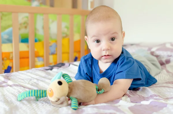 Pojke leker med mjuk leksak på sängen — Stockfoto