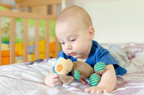 Pojke leker med mjuk leksak på sängen — Stockfoto