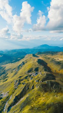 Scenic aerial photo of illuminated mountain ridge below dramatic summer clouds