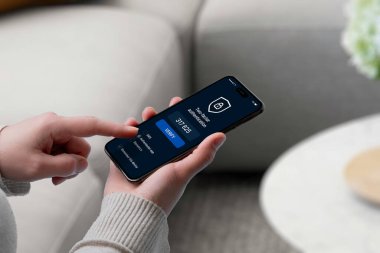 2FA kodunu akıllı telefon ekranına güvenlik kalkanı simgesi ile giren kullanıcı, güvenli giriş, doğrulama ve çok katmanlı kimlik doğrulamayı temsil ediyor