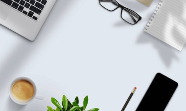 Dizüstü bilgisayar, defter, kahve, bitki ve akıllı telefon, modern dijital çalışma alanını temsil eden doğal gölgelerle aydınlatma masasında düzenlenmiştir.