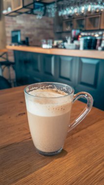 Süslü kafe barın içindeki ahşap masada duran bir bardak köpüklü kahve markalaşma ve yaşam tarzı görselleri için mükemmel bir iç tasarım.