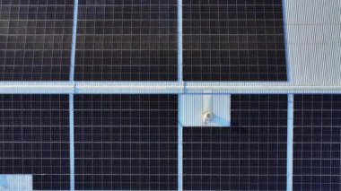 Endüstriyel çatıdaki güneş panellerinin hava aracı görüntüleri, temiz yenilenebilir enerji kurulumunu ortaya çıkarmak için kamera geri çekiliyor.