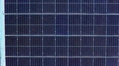 Endüstriyel binadaki güneş enerjisi alanından sola hareket eden İHA mavi fotovoltaik panellerin geometrik modelini gösteriyor.