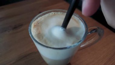 Makro kaşık şat köpüğü karıştırılmış cam bardak kahve, pürüzsüz doku ve ılık tonlarda, kafe veya yaşam tarzı görselleri için mükemmel.