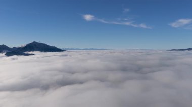 Kalın sisin üzerinde Trebeviç 'i gösteren İHA slaytı, turizm markalaşması, sinematik seyahat düzenlemeleri ve atmosferik kış manzarası görüntüleri için ideal.