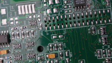 Çipler, kondansatörler ve lehimlenmiş bileşenleri olan yeşil devre kartının makro dönüşümlü görüntüsü, ayrıntılı elektronik ve donanım mühendisliği yapısını gösterir