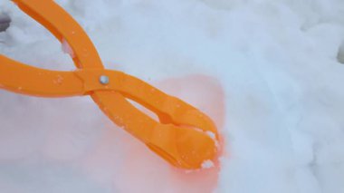 Çocuk kartopu oluşturmak için plastik alet kullanıyor, neşeli kış eğlencelerini ve taze karda neşeli açık hava aktivitelerini yakalıyor