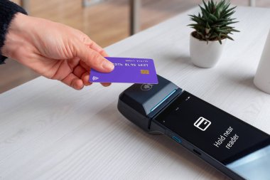 POS uçbirim ekranında kablosuz NFC ödeme süreci sırasında okuyucu iletisinin yanında beklemede tutulduğunu gösteren temassız kart ödeme talimatı