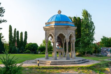 Zica Manastırı kompleksinde mavi kubbeli taş pavyon, yeşil alanlarla çevrili barışçıl Ortodoks mimari detayı.