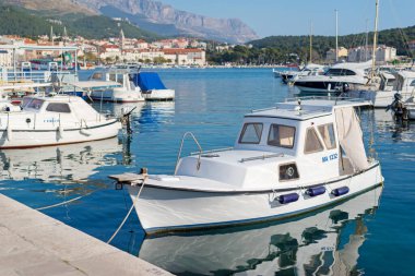 Makarska, Hırvatistan, 31 Mart 2019 Arka planda kasaba limanı ve Biokovo dağ sırası bulunan marinada demirlemiş küçük bir motorlu tekne.