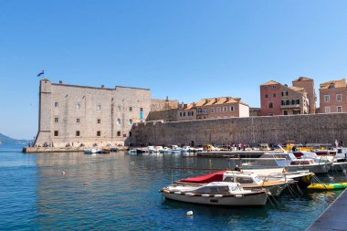 Dubrovnik, Hırvatistan, 01 Mayıs 2022 Tarihi taş duvarlar ve açık mavi gökyüzü altında liman mimarisi ile Eski Kent Limanı yakınlarında demirlemiş tekneler