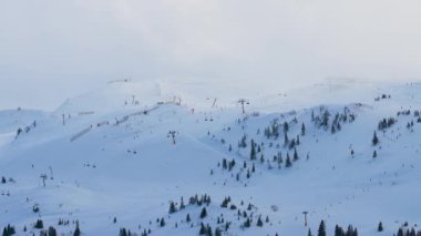 Yumuşak sisle kaplı kar manzarasının minimum hava görüntüsü, kış sessizliğini, izolasyonu ve atmosferik dağlık manzarayı vurguluyor