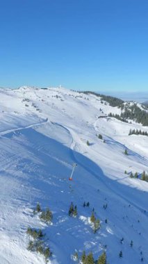 Bakımlı yamaçlı Jahorina kayak merkezinin dikey hava manzarası, kış turizminin tanıtımı ve sosyal medya alp sporu içeriği için ideal
