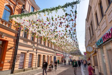 Banja Luka, Bosna-Hersek 22 Nisan 2023 Gospodska Caddesi boyunca yürümekte olan insanlar bahar döneminde şehir merkezinde renkli asılı çiçeklerle süslenmiş.