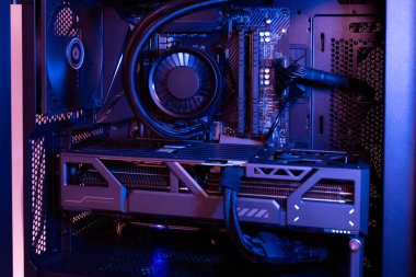 Grafik kartı, sıvı soğutma sistemi, anakart ve güç tedarik kabloları koyu modern aydınlatmayla aydınlatılmış yüksek performanslı masaüstü bilgisayarı.