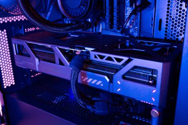 Görünür soğutma sistemi, güç bağlantıları ve mavi ışık altında dahili donanıma sahip modern bir masaüstü bilgisayar çantasına yüklenmiş grafiksel kart