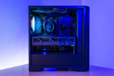 Çağdaş oyun masaüstü bilgisayarı şeffaf durumda, sıvı soğutma, grafik kartı ve rgb ışıklandırması, minimalist çalışma ortamında masanın üzerine yerleştirilmiş