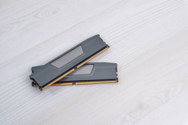 Hafif ahşap masaya yerleştirilmiş iki RAM bellek modülü, güncelleme veya yenileme için hazırlanmış bilgisayar donanımı bileşenleri