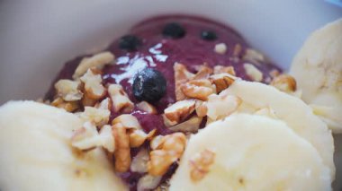Makro yavaş çekim ceviz üzerine taze yaban mersini ve yulaf ezmesi üzerine muz, canlı sağlıklı kahvaltı kompozisyonu