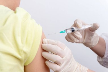 Tıbbi aşı sırasında klinikteki hastanın koluna aşı enjekte eden doktoru kapatın.