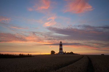 Gökyüzünde dramatik bir günbatımı rengi Happisburgh 'da Norfolk sahillerinde ikonik deniz feneriyle