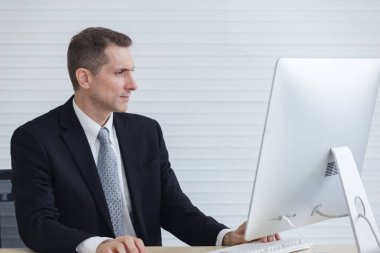 Ofisinde çalışan bir iş adamı, masaüstü bilgisayarı kullanan bir adam..