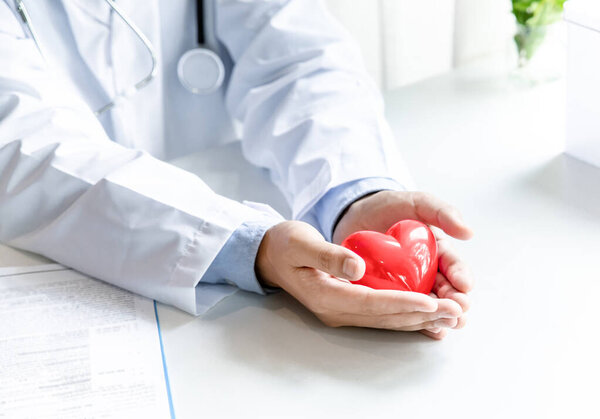 Красное сердце в руках врача в больничном офисе. медицинское обслуживание и здравоохранение.
