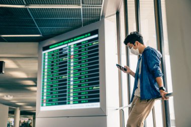 Asyalı adam rezervasyon yapmak ya da giriş yapmak için akıllı telefon kullanıyor..