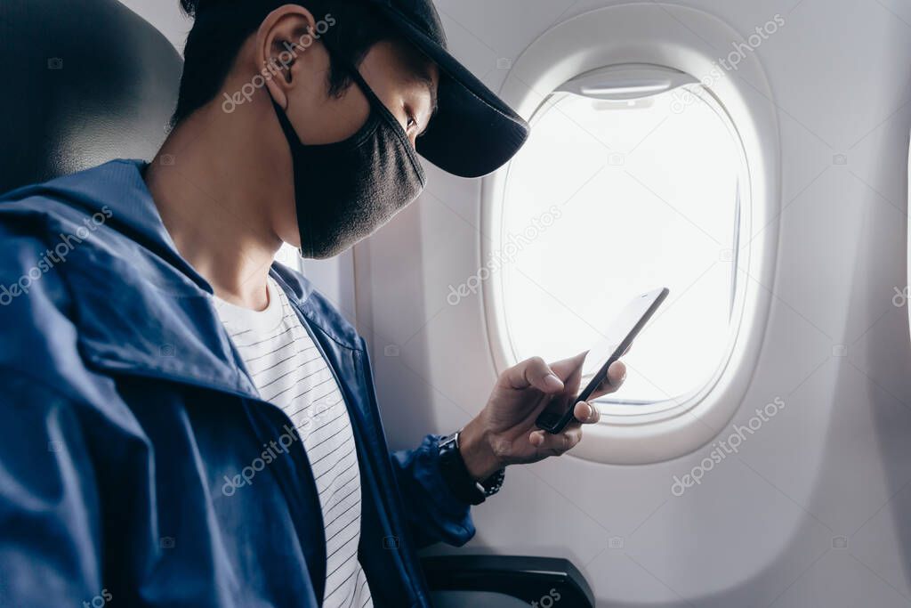 Man wear face mask and using smart phone on airplane
