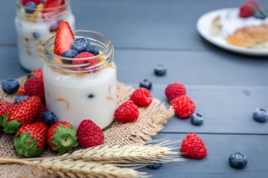 Üstünde çilek olan bir kavanoz yoğurt, kahvaltı ve sağlıklı yemek..