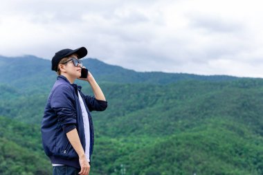 Uçurumun kenarında duran ve akıllı telefonu kullanan bir gezgin..