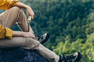 Elinde harita, uçurumun kenarında oturan bir gencin eli..